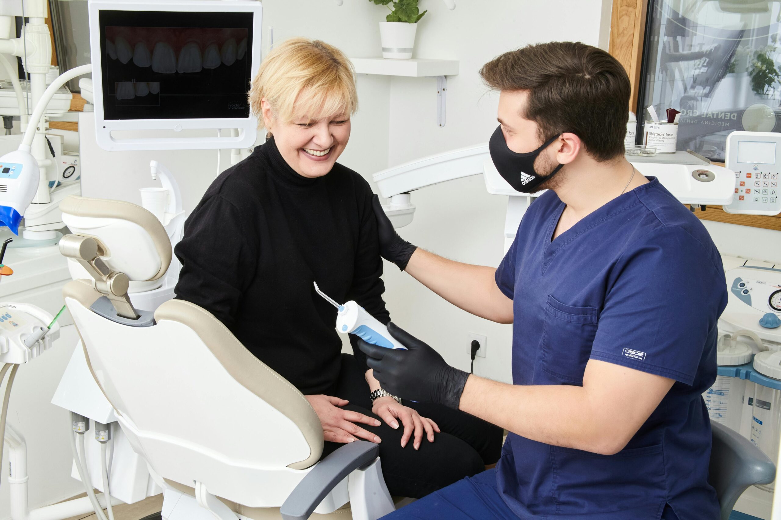 A dentist in Belgrade offers a friendly consultation to a smiling patient in a modern clinic.